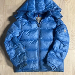 Blå dunjacka från Moncler - Säljer en snygg blå dunjacka från Moncler med huva och dragkedja. Jackan har långa ärmar och en klassisk Moncler-logga på ärmen. Storlek 160 cm. Riktigt snygg för styling. Perfekt för kyligare dagar.  OBS, Tar inte i mot tillbaka skickningar om du köper du behåller du den.    Tack MVH, Vinzent 