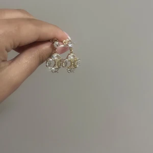 Guldiga örhängen med kristaller - Eleganta örhängen i guld med gnistrande kristaller. Designen har en central guldfärgad detalj omgiven av klara stenar som ger en lyxig känsla. Perfekta för att ge en touch av glamour. Helt nya! Köpta i Spanien 🇪🇸 guldpläterat rostfrittstål ✨