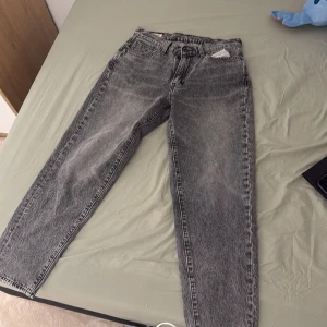 Grå jeans från Levi's - Snygga grå jeans från Levi's med klassisk femficksdesign och knappgylf. Perfekta för en avslappnad stil med en rak passform som ger en tidlös look.