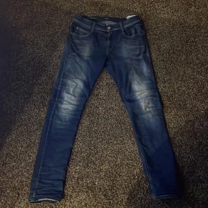 Blå jeans från Replay  - Snygga blå jeans från Replay med en slim passform. De har en klassisk femficksdesign och en knappgylf. Perfekta för en stilren look. Nypris i butik ca 1400-1500kr. Storlek: W30 L32