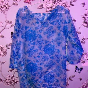 Blå mönstrad blus från Yves Rocher - Säljer en blå klänning från Yves Rocher med ett unikt mönster. Klänningen är tillverkad i 100% polyester och har trekvartsärmar. Perfekt för dig som vill ha något speciellt i garderoben! 💙