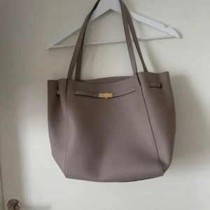 Väska från H&M  - Grå/beige med guld detalj. Jätte fin och rymmer mycket. 