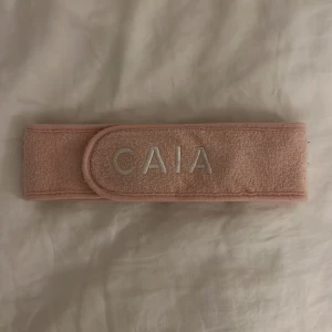 Rosa hårband från CAIA - Snyggt rosa hårband från CAIA med broderad logga framtill. Perfekt för att hålla håret borta vid sminkning eller hudvård. Mjukt och bekvämt material.