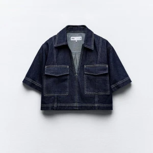 Mörkblå croppad jeans topp från Zara - Snygg mörkblå croppad jeans topp från Zara med korta ärmar och två stora fickor framtill. Toppen har en stilren look och en klassisk krage. Perfekt för en trendig look! Helt ny med prislapp på.