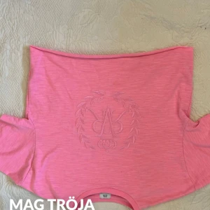 Rosa croppad topp från River island - Säljer en söt rosa croppad topp från River island med ett diskret emblem på framsidan. Toppen har korta ärmar och en avslappnad passform. Perfekt för varma dagar eller som ett lager under en jacka. Hör av dig vid intresse! 💖