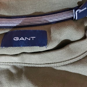 Olivgrön sweatshirt från GANT - Säljer en olivgrön sweatshirt från GANT med broderad logotyp på framsidan. Tröjan har rund hals och långa ärmar, perfekt för en avslappnad stil. Passar bra till både jeans och chinos.