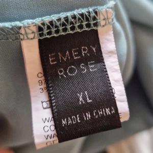 Blå långärmad topp från Emery Rose - Säljer en stilren blå långärmad topp från Emery Rose i storlek XL. Perfekt för både vardag och lite finare tillfällen. Toppen har en enkel design med en liten v-ringning som ger en snygg detalj. Materialet är mjukt och bekvämt, vilket gör den skön att bära hela dagen.