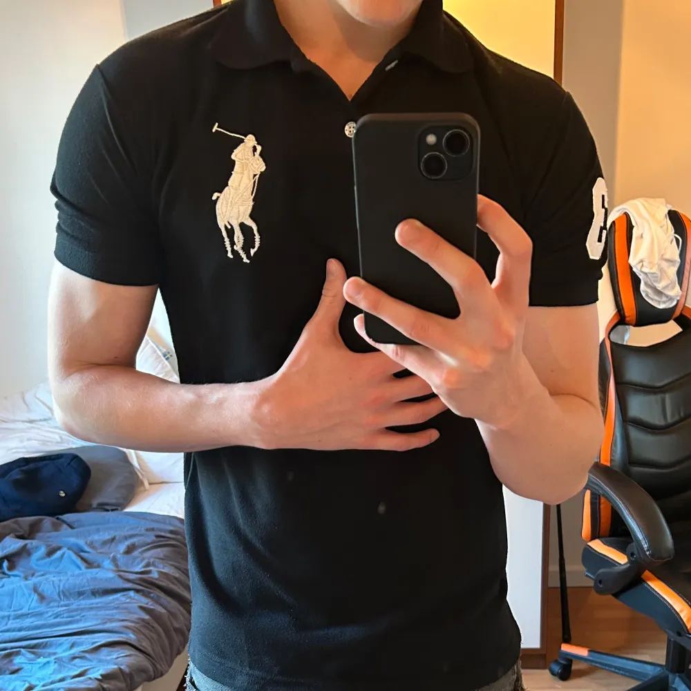 Säljer en klassisk svart pikétröja från Polo Ralph Lauren i storlek M. Tröjan har en broderad logga på bröstet och siffran 3 på ärmen. Perfekt för en stilren och sportig look. Tillverkad i 100% bomull för en bekväm passform. Modell: 182 cm och väger 72 kg. Skjortor.