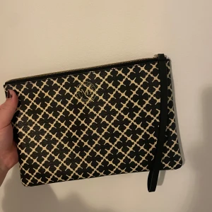 Marlene birger - Snygg kuvertväska med ett stilrent mönster i svart och beige. Väskan har en praktisk dragkedja och en diskret logga på framsidan.  Äldre modell, lite större. Super snygg och i mycket bra skick!