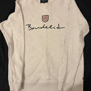 Grå sweatshirt från Bondelid - Säljer en stilren grå sweatshirt från Bondelid i storlek L. Tröjan har ett klassiskt tryck på bröstet och är perfekt för både vardag och avslappnade tillfällen. Den är i mycket bra skick och superbekväm att ha på sig. Passar perfekt till jeans eller chinos!