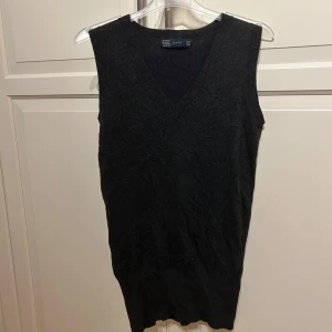 Svart/grå väst  från Zara - Snygg svart grå väst från Zara i ett mjukt och stretchigt material. Perfekt för lager-på-lager-stil eller som ett stilrent plagg för sig själv. Den har en v-ringad design som ger en klassisk look.
