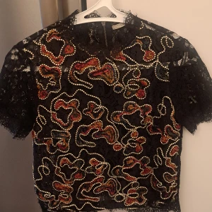 Blus från Zara - Jättefin spetsblus med svart botten och superfint mönster fram i olika färger! Fin både till fest och vardags! Dragkedja i ryggen.