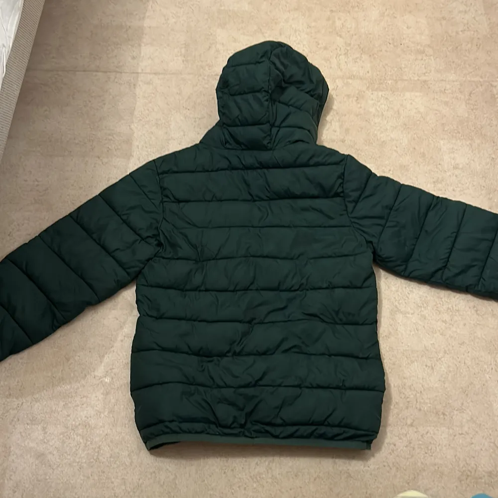 Säljer en grön pufferjacka från Lyle & Scott i storlek 10/11 år. Jackan har en mysig huva och dragkedja framtill. Perfekt för kyliga dagar! Den är i bra skick med en liten reva vid ärmslutet som går och fixa med några stygn. Passar både höst, vår och vinter.. Takit.