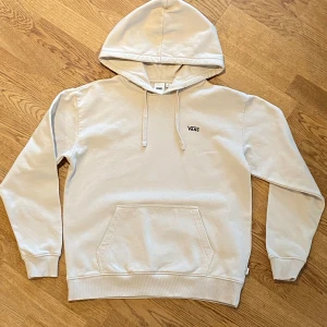 Beige hoodie från Vans - Säljer en snygg beige hoodie från Vans i mycket bra skick. Den har en stor ficka fram och ett coolt blommigt mönster med Vans-logga på ryggen. Perfekt för höst och vår! 🧢
