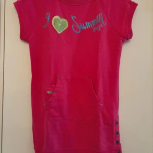 Rosa klänning från Diesel - Säljer en superfin unik rosa klänning från Diesel med texten 'I ♥ Summer' och en lime-detalj. Den har korta ärmar och en praktisk ficka framtill. Perfekt för vår/höstdagar eller kallare dagar då klänningen är i ett lite tjockare material ! 🌞 Köparen betalar frakt. 