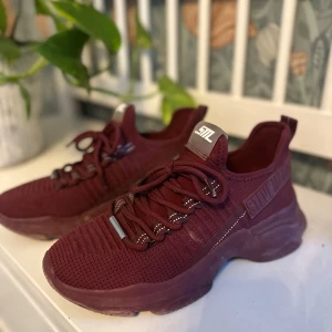 Vinröda sneakers från Steve Madden - Säljer ett par snygga vinröda sneakers från Steve Madden. De har en stickad look med snörning och en chunky sula som ger extra höjd. Perfekta för både vardag och fest! 🏃‍♀️✨