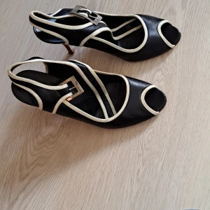 Stilettklackar - Stilettklackar med röd klack,  och vita kontrasterande kanter. De är inte i jättebra skick och lite vingliga, skulle inte rekommendera till någon som inte är van vid att gå klackar. Okänt märke och köpt second hand, de är troligen vintage. 