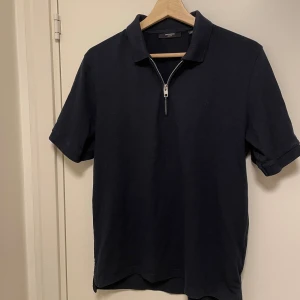 Piké med zip - Stilren mörkblå pike med zip från Jack and Jones! Säljer tröjan då den är för liten, endast använt ett fåtal gånger. 10/10 skick! Spara 190kr genom att köpa denna för 159!