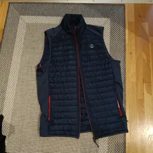 En fin Jack & Jones vest i marinblå med röda accenter.  Skick ~ 9/10, använd fåtal gånger.  Storlek S