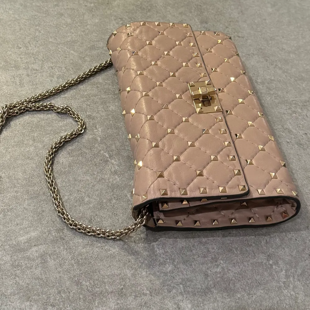 Jag säljer min otroligt fina ROCKSTUD SPIKE NAPPA LEATHER CROSSBODY CLUTCH BAG i färgen Poudre. Väskan är i mycket bra skick.🩷 Ny pris 20 975kr. Pris går att diskutera. Skriv för fler bilder🫶🏽. Väskor.