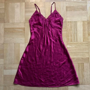 Rosa sidenklänning med spetsdetaljer - Superfin mörkrosa klänning i siden med spetsdetaljer vid bysten. Smala justerbara axelband! 