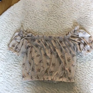 Sommarblus, beige med rosa blommor. Ginatricot, ganska kort - Säljer en sommarblus i storlek M. Typ silkesmaterial, väldigt stretchig. Kort vid magen