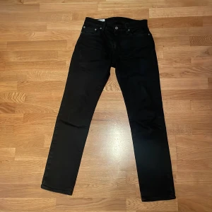 Svarta jeans från Levi's - Säljer ett par svarta jeans från Levi's i storlek W29 L32. De har en klassisk design med fem fickor och knappgylf. Jeansen är i bra skick och passar perfekt för både vardag och fest. De är tillverkade i ett slitstarkt material som håller länge. Modell: 511