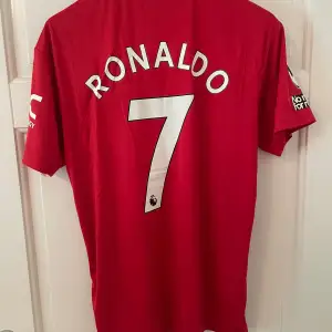 Säljer en fotbollströja från Manchester United med Ronaldo #7 på ryggen. Trycket vid sponsorn är lite sprucket enligt sista bilden. Tröjan är en reprint. Storlek: M. Ansvarar ej för postens slarv. Endast handtvätt gäller, gnugga ej på blöta prints.