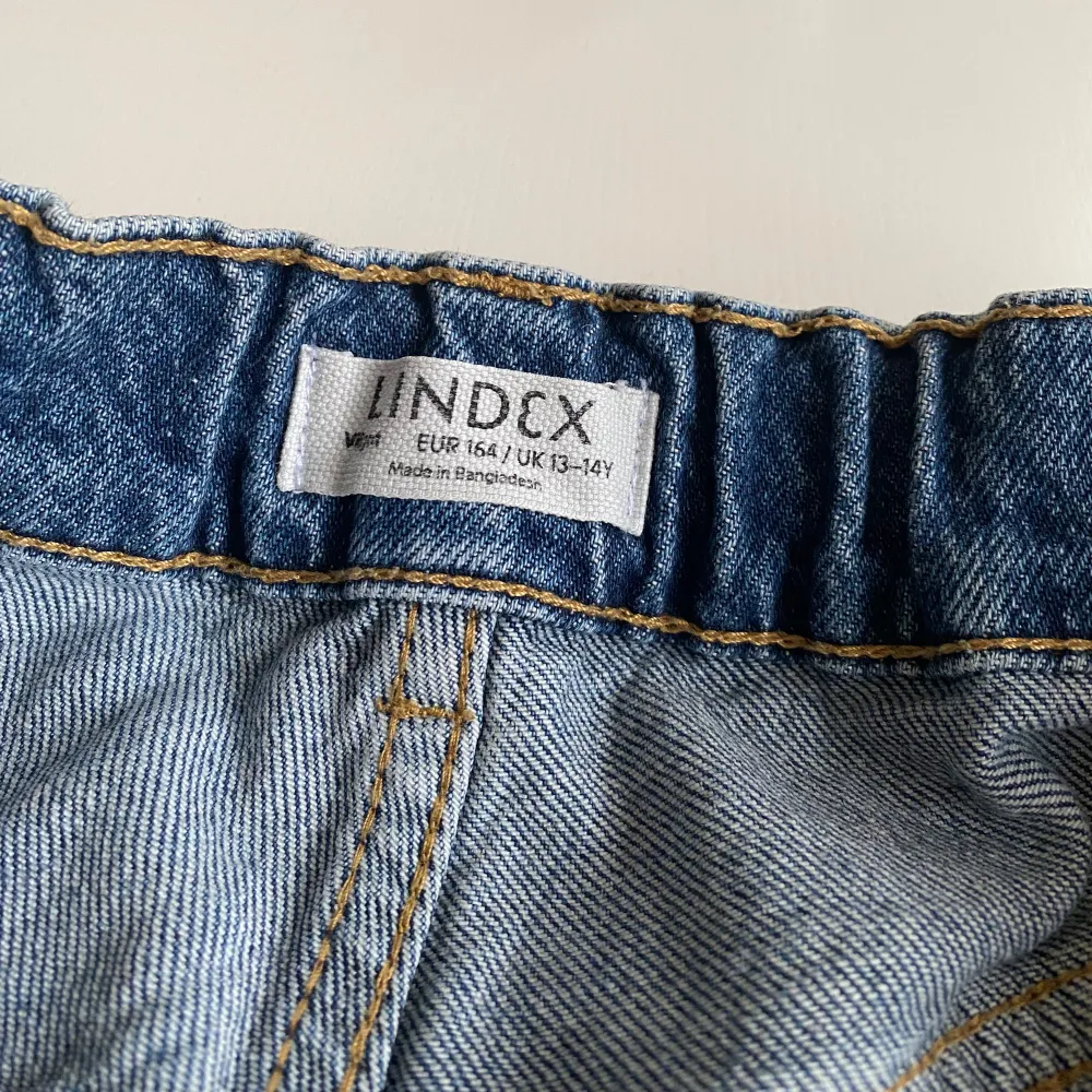 Säljer ett par klassiska blå jeans från Lindex i storlek 164. De har en elastisk midja för extra komfort och två bakfickor. Perfekta för vardagsbruk och passar till det mesta. Skicket är bra och de är redo för en ny ägare! Straight fit!. Jeans & Byxor.