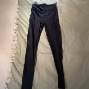 Svarta leggings - Säljer ett par svarta leggings som är superbekväma och perfekta för både träning och vardag. De är högmidjade och har en tight passform som sitter snyggt på kroppen. Materialet är mjukt och stretchigt, vilket gör dem sköna att ha på sig.