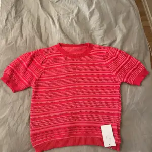 Säljer en superfin röd stickad tröja från Knit Max. Den har ett coolt randigt mönster och korta ärmar, perfekt för vår och sommar. Tröjan är i nyskick och har fortfarande etiketten kvar. Passar perfekt för en avslappnad men stilren look!