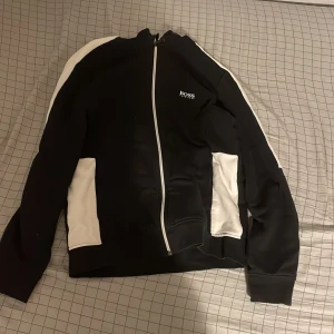 Hugo Boss Zip tröja - Tja säljer en Hugo boss tröja. Skicket är 9/10. Använt den Max 10 ggr. Inga hål. Passar dig som är ca 165 cm