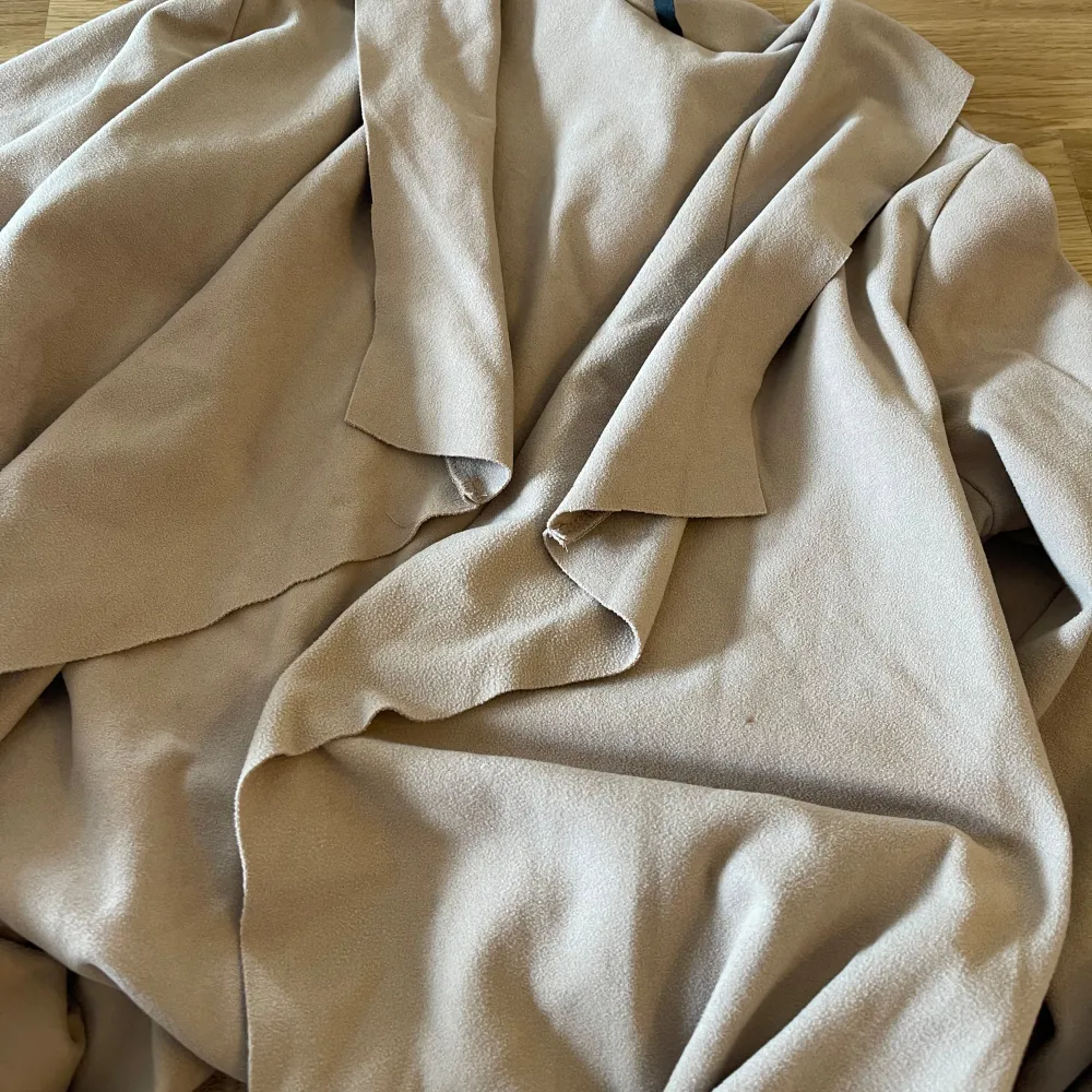 Säljer en snygg beige trenchcoat från Shein. Den har en stilren design med långa ärmar och en öppen front utan knappar. Perfekt för både vardag och fest! Materialet är tunt, mjukt och bekvämt.. Jackor.