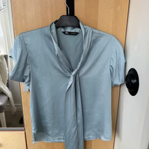 Vacker blå blus med knytning vid halsen - Elegant blå blus i silkesmaterial från zara. Mycket bra skick.