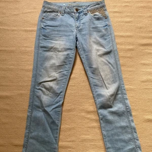 Ljusa jeans med broderade detaljer - Säljer ett par ljusa jeans. De har snygga broderade detaljer på fickorna både fram och bak. Jeansen har en klassisk femficksdesign och stängs med en knapp och dragkedja. Perfekta för en avslappnad vardagslook! Köpta second hand men inte använda så mycket av mig pga lite för stora, men ändå fint skick. low -> mid rise skulle jag säga.