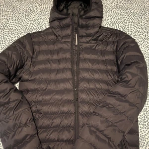 Svart pufferjacka från Etirel - Säljer en svart pufferjacka från Etirel i storlek S. Jackan är quiltad och har en dragkedja framtill. Perfekt för kalla dagar med sin varma och bekväma design. Den har en huva för extra skydd mot väder och vind. Passar både till vardags och utomhusaktiviteter.