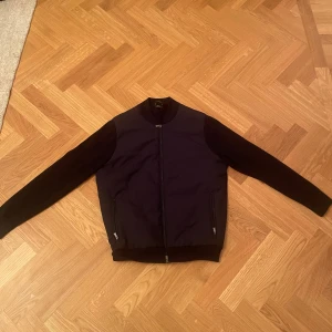 Blå cardigan från Massimo Dutti - Säljer en stilren marinblå cardigan från Massimo Dutti. Jackan har en dragkedja framtill och ribbade muddar vid krage, ärmslut och nederkant. Använd 2 gånger.                                                    Jacka, tröja, marin