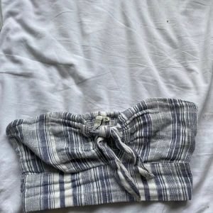 Randig tubtopp från NLY Trend - Säljer en superfin randig tubtopp från NLY Trend i storlek 34. Den är blå och vit med ett snyggt knytband framtill. Perfekt för sommardagar på stranden eller en avslappnad dag i stan. Toppen är i bra skick och redo för nya äventyr!