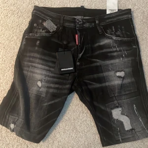 Svarta jeansshorts från Dsquared2 - Säljer ett par svarta jeansshorts från Dsquared2. De har en cool slitningseffekt och en klassisk femficksdesign. Shortsen har en knappgylf och är i nyskick. Perfekta för en avslappnad sommarlook!