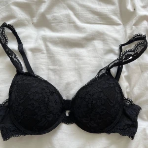 Svart spets-bh  - Säljer en elegant svart spets-bh från Lindex i modell Rebel. Den har vackra spetsdetaljer och justerbara axelband för bästa passform. Den har lite push-up. Perfekt för både vardag och speciella tillfällen. Köp direkt eller ge prisförslag 💛