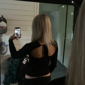 Svart tröja med öppen rygg  - Svart ribbad långärmad tröja med öppen rygg, den är som ny eftersom den aldrig kommit till användning💕Man kan själv bestämma hur mycket den ska sitta åt eftersom man själv knyter där bak!💕💕