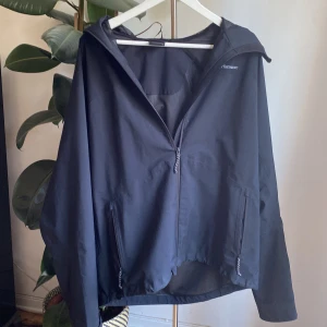 Svart vindjacka från Peak Performance - Säljer en svart vindjacka från Peak Performance i storlek XL. Jackan har en dragkedja framtill och är tillverkad i ett slitstarkt material med HIPE-teknologi för extra skydd mot väder och vind. Perfekt för utomhusaktiviteter och träning.