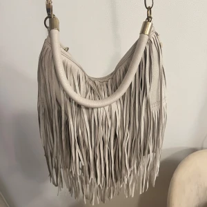 Väska med fransar  - Fin väska med fransar med ett långt och ett kort axelband, väskan är i väldigt fint skick och är som ny! 