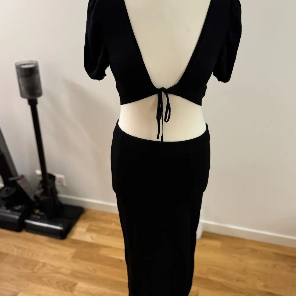 Säljer en elegant svart klänning från Fashion Nova. Den har en djup öppen rygg med knytband och korta ärmar. Perfekt för en festkväll eller en speciell tillställning. Klänningen är tight och framhäver figuren på ett snyggt sätt.. Mekot.