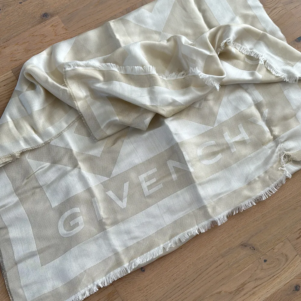 Beige/vit scarf från Givenchy. Äkta, men saknar tyvärr kvitto och tillbehör eftersom det var en present. Finns några få skavanker, (se bild 4 och 5). Annars är scarfen i jättefint skick och i princip oanvänd.. Accessoarer.