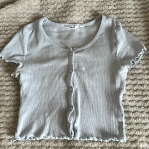 Ljusblå ribbad topp med knappar - Säljer en söt ljusblå topp som är i storlek 152 men är väldigt stretchig så funkar oxå för större storlekar. Har knappast använt den så den e i bra skick (priset kan diskuteras)💙🤍