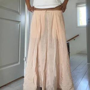Ljusrosa långkjol  - Kjolen går hela vägen ner till fötterna på mig som är 173! Den är i mycket gott skick. Kjolen är stretchig i midjan, funkar även för en 36/38, och har två fickor framtill. Materialet är tunt och skönt men kan bli lite genomskinligt i vissa ljus😊