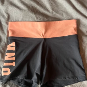 Victoria secret/PINK hotpants - Säljer ett par hotpants/shorts från PINK/Victoria secret i storlek S. Grå med lite orangea detaljer! Skönt träningsmaterial. Säljer för 125kr😊
