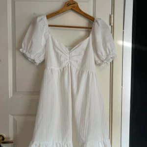 Vit klänning  - Medel lång vit klänning. Man kan välja om man vill dra ner axlarna eller inte 