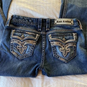 Rock revival jeans bootcut  - Fetaste Rock Revival jeansen med flera olika knappar, nitar och stenar.  Jeans är i strl 29, lågmidjade och omsydda bootcut(se bild). Priset kan diskuteras💋